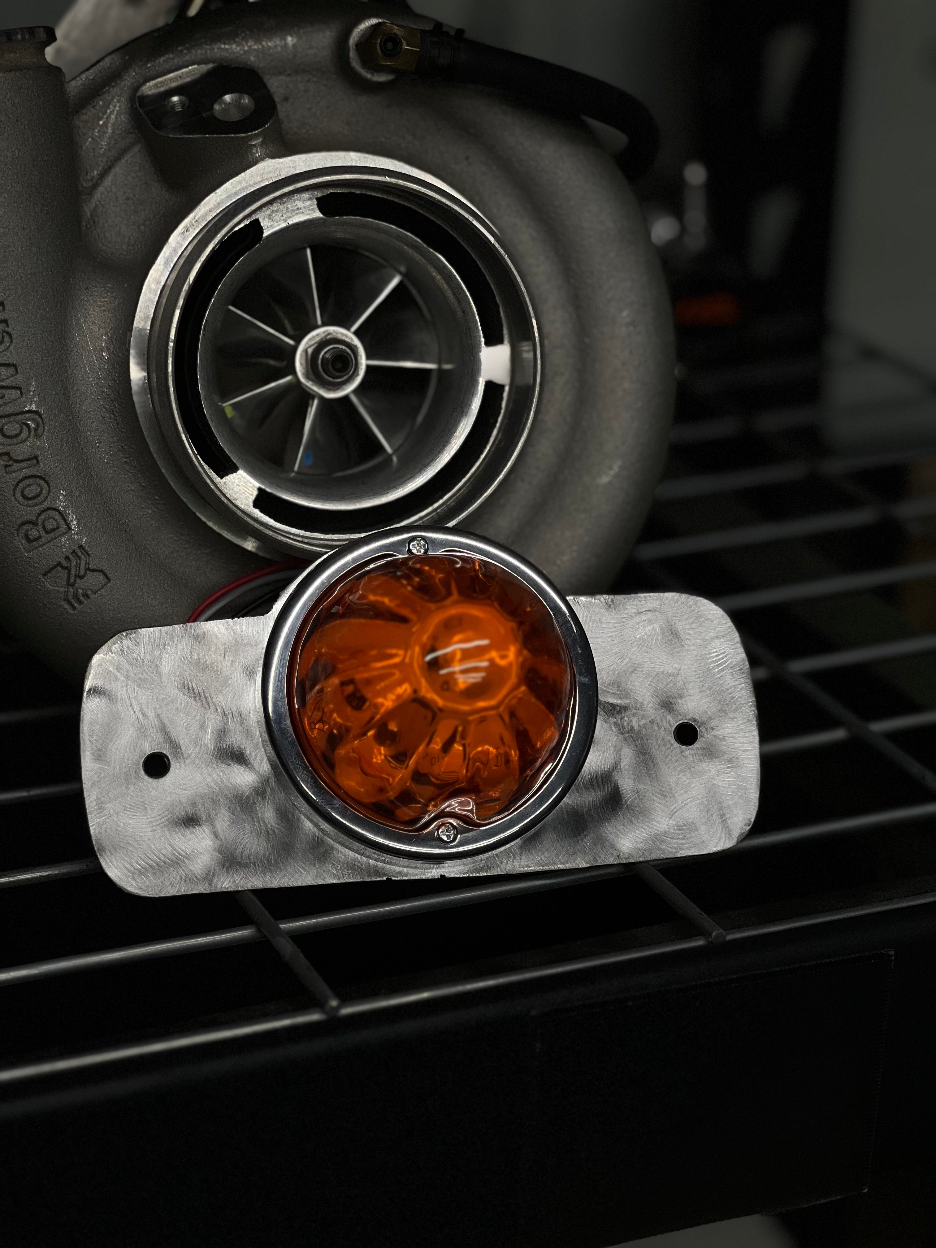 Amber watermelon glass dome light on its mounting plate in front of a turbo