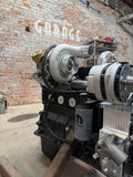 High-mount turbo on a Cummins with Brown Bros. oil feed and drain lines, in front of the Brown Bros. Garage brick wall