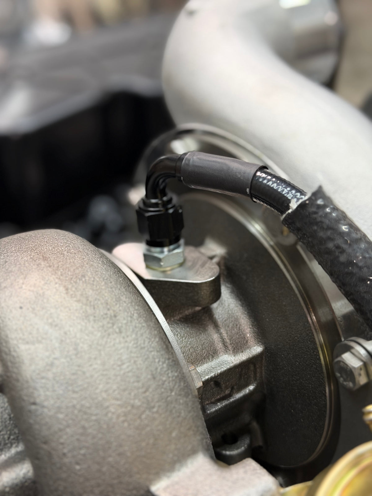 Braided oil feed line with heat sleeve at the turbo
