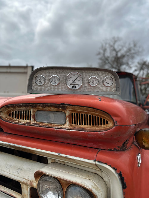 Chevy gauge cluster sitting on the hood of a classic Chevy truck