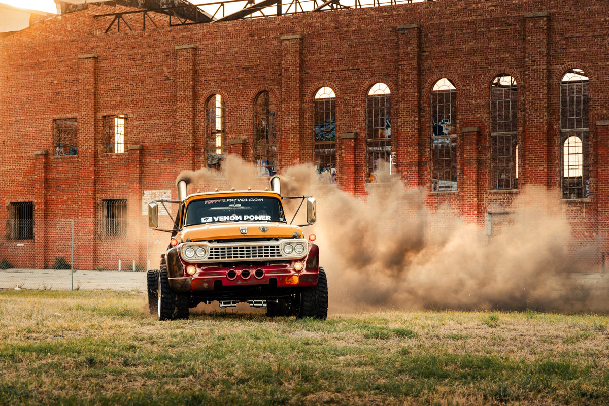 Ronald McDonald, the 1958 Ford F700 crew cab, kicking up dust in front of a brick building
