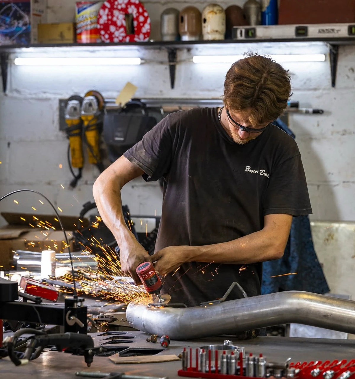 Brown Bros. crew member grinding a custom pipe in the shop, sparks flying