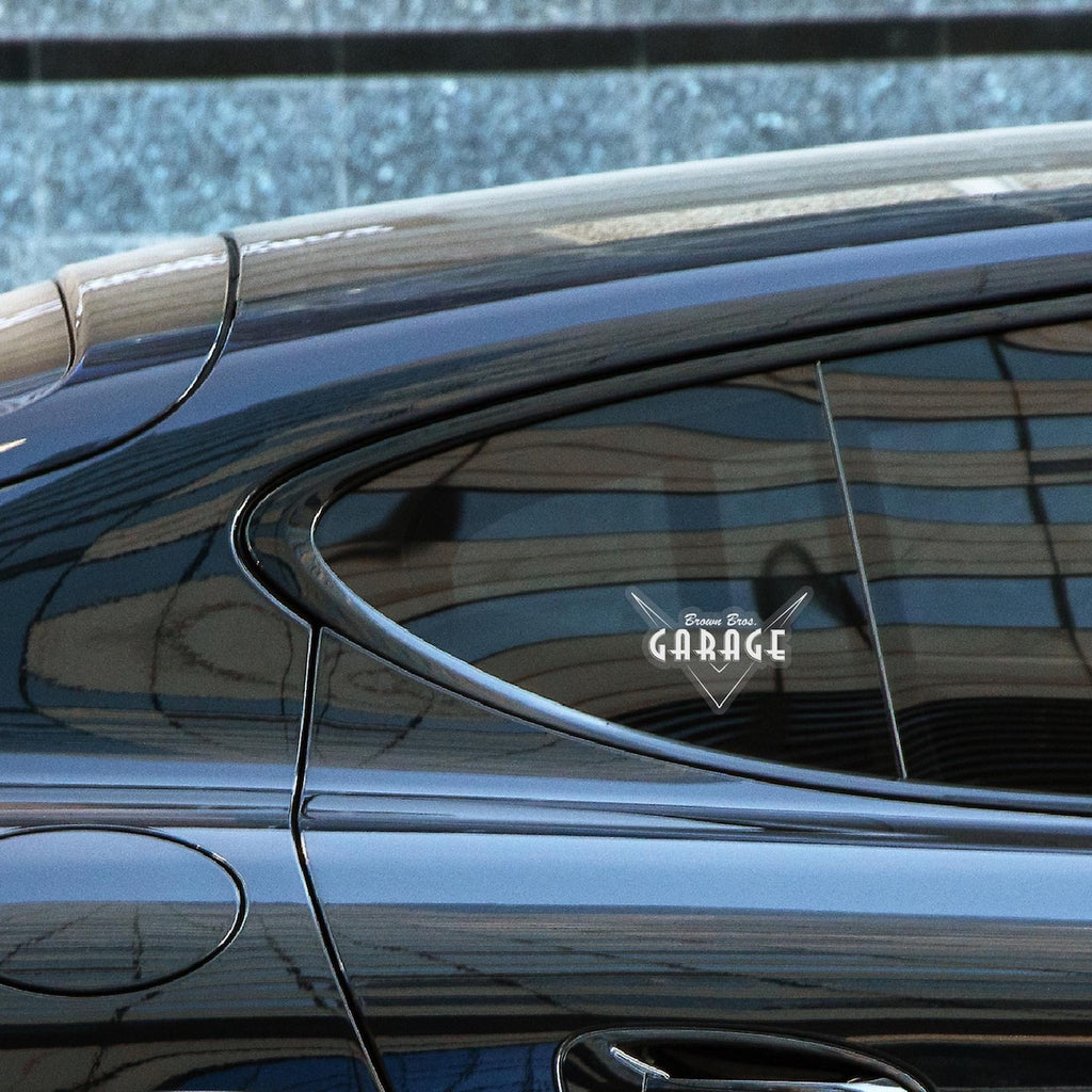 Clear Brown Bros. Garage logo sticker on a dark car's rear side window