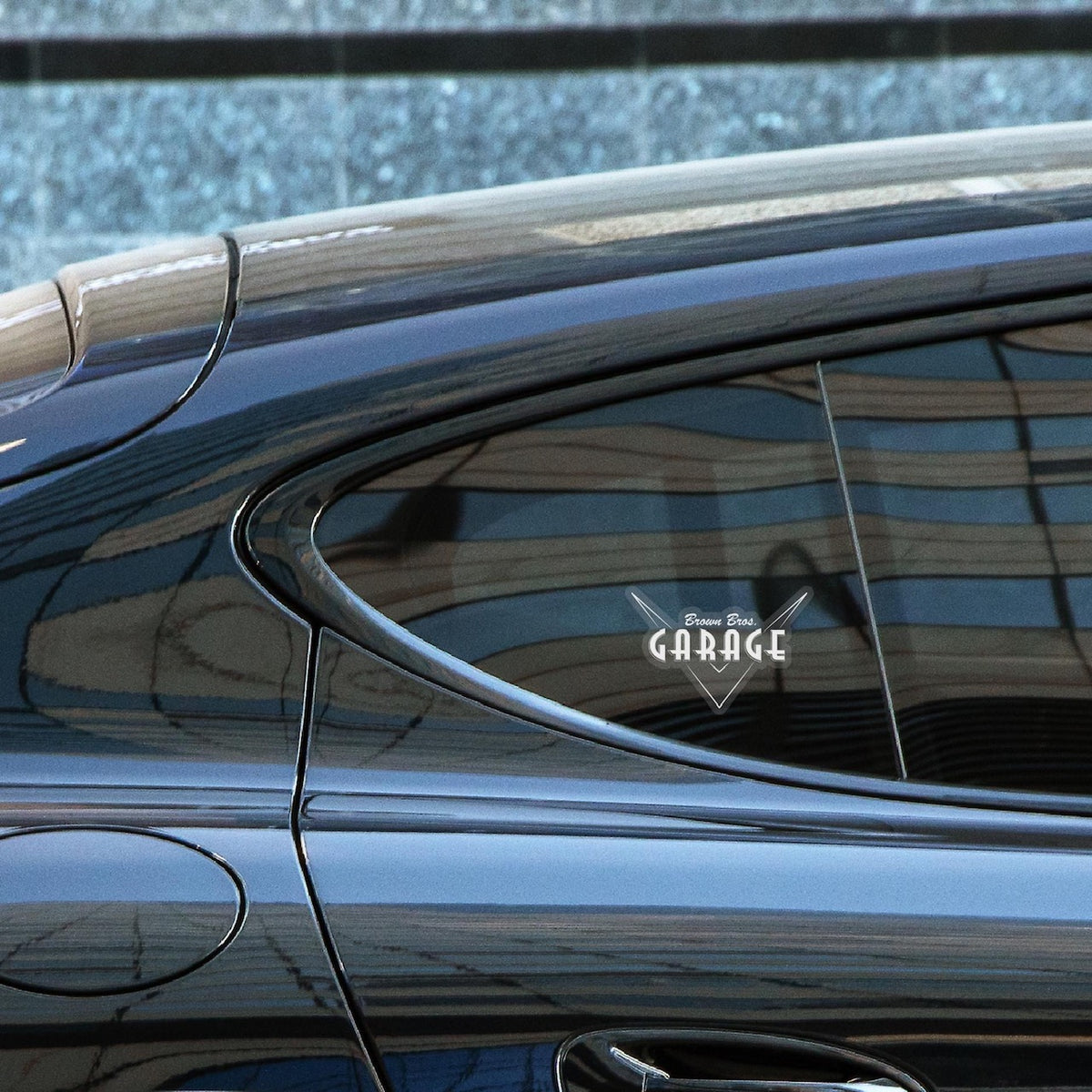 Clear Brown Bros. Garage logo sticker on a dark car's rear side window