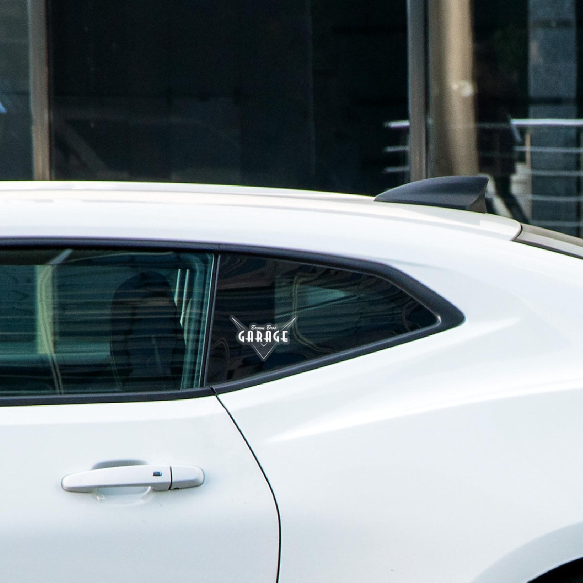 Clear Brown Bros. Garage logo sticker on a white car's rear window